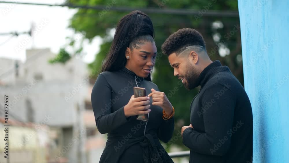 Candid person showing content on phone screen to friend outside Candid person showing content on phone screen to friend outside