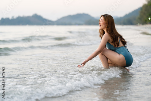 cheerful woman in swimsuit playing water splashing on the sea beach at Koh Chang island  Thailand