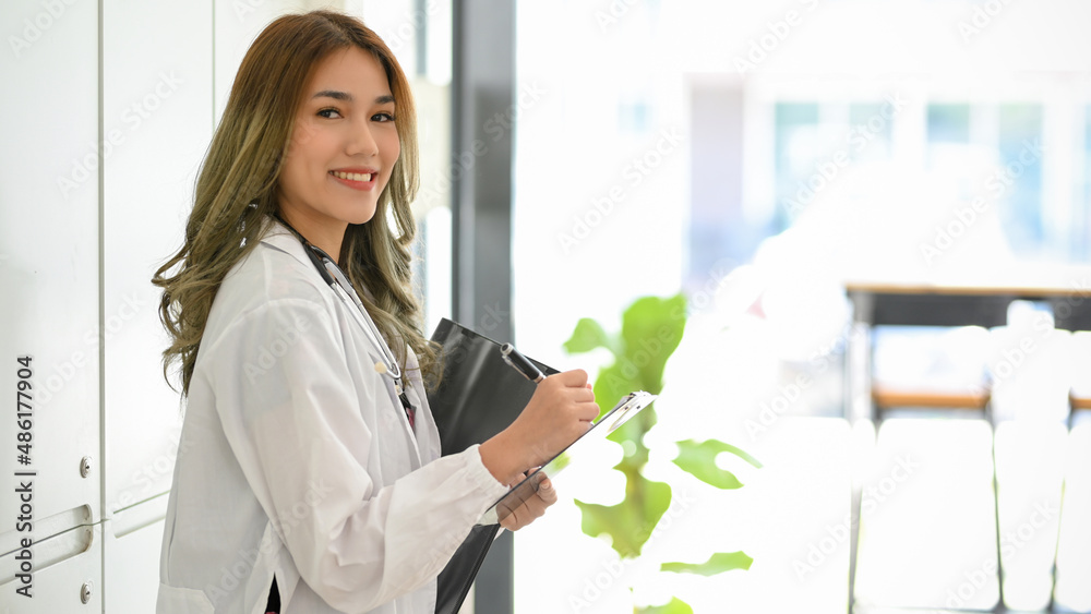 Female doctor in white uniform writing a drug prescription on medical clipboard Female doctor in white uniform writing a drug prescription on medical clipboard