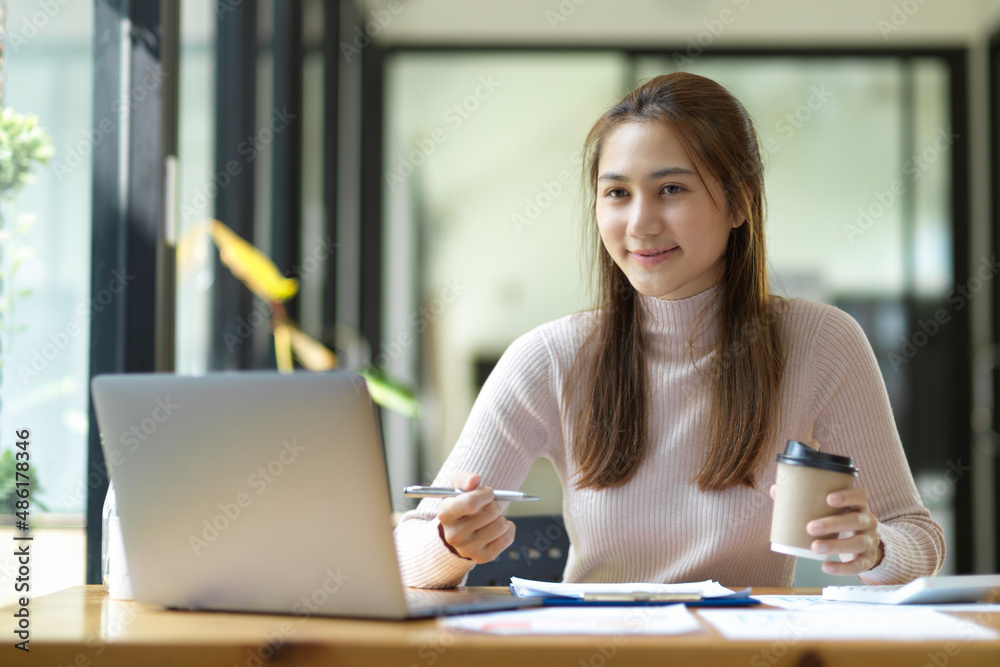 Businesswoman or female officer sipping coffee while working on laptop Businesswoman or female officer sipping coffee while working on laptop