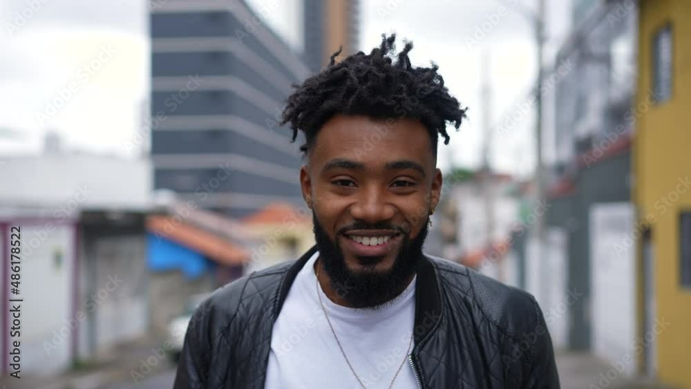 A happy young African man walking in urban street going forward A happy young African man walking in urban street going forward