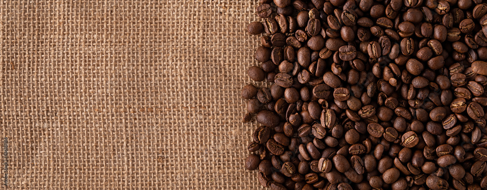 Toasted Coffee beans close up on burlap background. Panoramic image. Top view with copy space for your text. Toasted Coffee beans close up on burlap background. Panoramic image. Top view with copy space for your text.