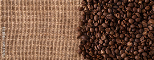 Toasted Coffee beans close up on burlap background. Panoramic image. Top view with copy space for your text.