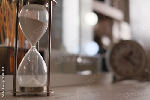 Hourglass as time passing concept for business deadline, sandglass urgency and running out of time run, wooden background with copy space.