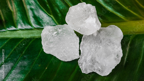 Crystal clear alum cubes or Potassium alum on green leaf. Chemical compound substance. Concept for beauty , spa and underarm treatment industrial. 