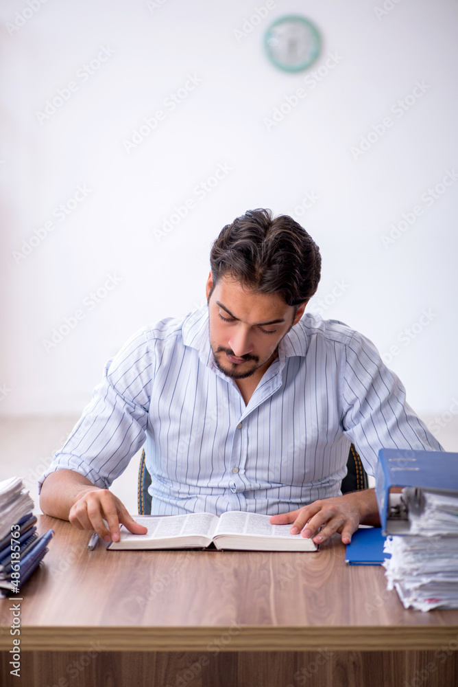 Young male employee and too much work in the office Young male employee and too much work in the office