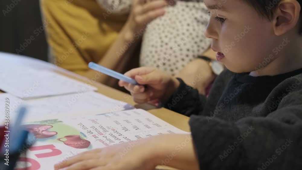 Boy reading the condition of the exercise and starting to write with a pen. Family hobby. Boy reading the condition of the exercise and starting to write with a pen. Family hobby.