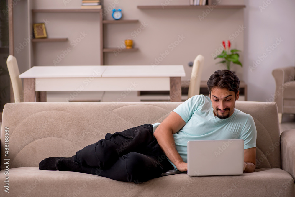 Young man sitting on the sofa with computer at home Young man sitting on the sofa with computer at home