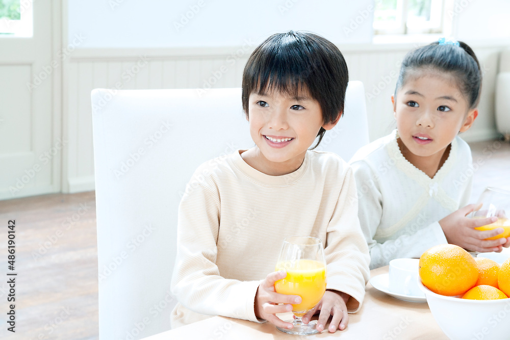 オレンジジュースを飲む男の子と女の子