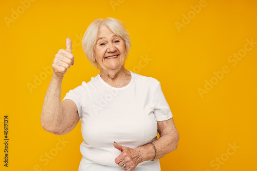 Portrait of an old friendly woman posing face grimace joy yellow background