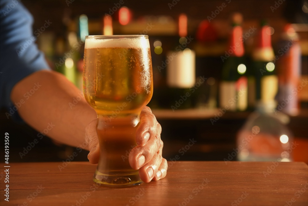 person holding a glass of beer in bar