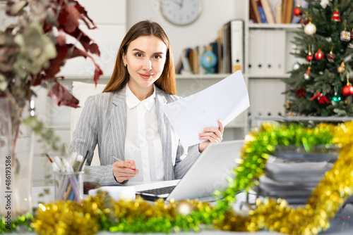 Office manager works with documents and laptop in office during christmas © JackF