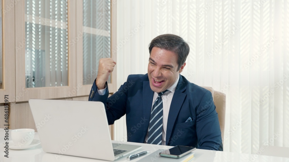 Business man sitting using laptop study online work at his desk success celebration at office, Smiling happy businessman cheerful in casual office making phone call while working with laptop computer Business man sitting using laptop study online work at his desk success celebration at office, Smiling happy businessman cheerful in casual office making phone call while working with laptop computer