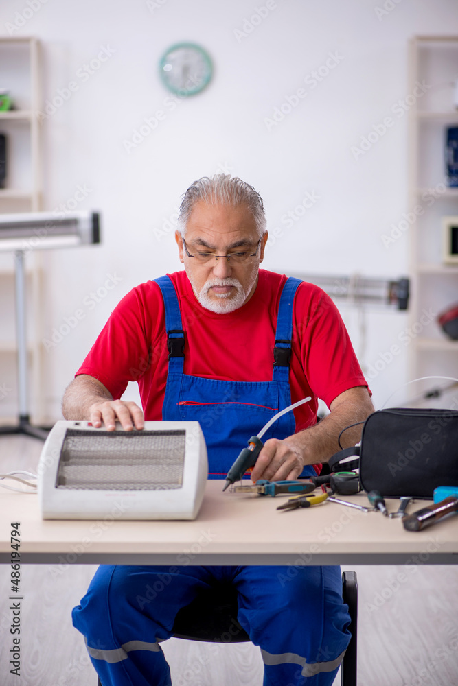 Old repairman repairing heater at workshop Old repairman repairing heater at workshop