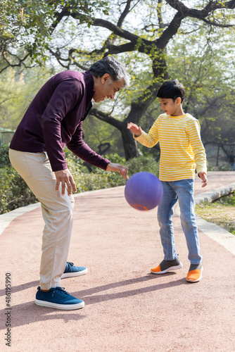 Father and son playing with ball at park 