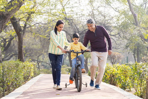 Parents teaching son riding bicycle at park