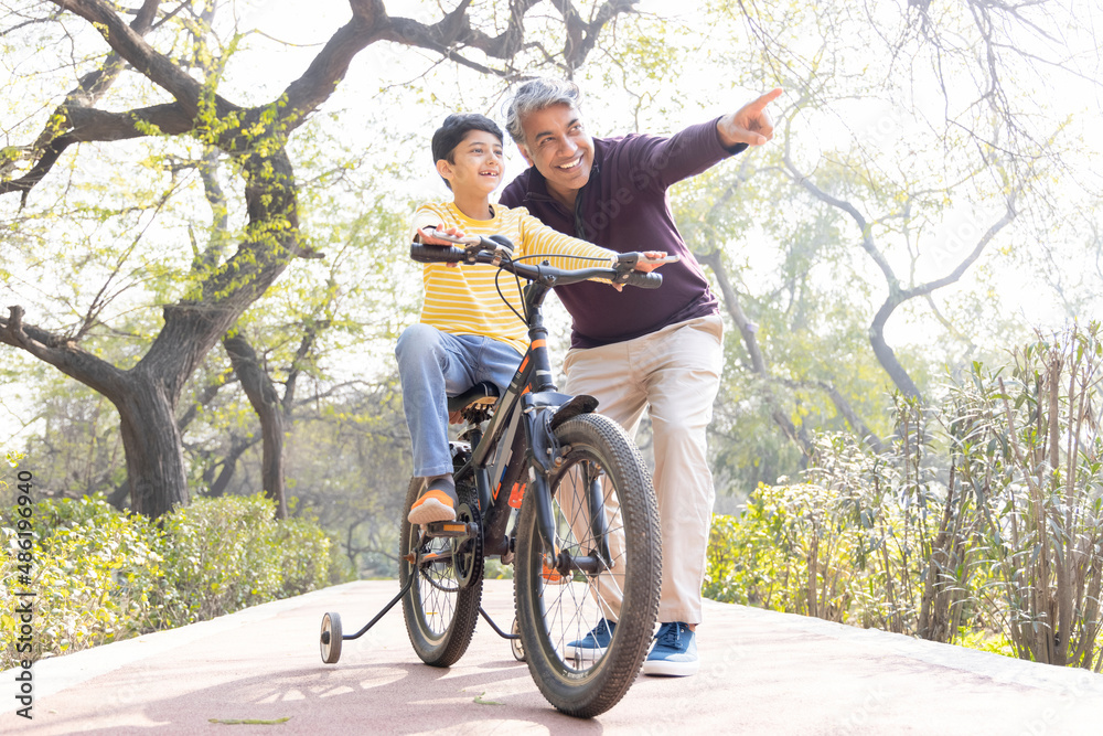 Fototapeta premium Father teaching son riding bicycle at park