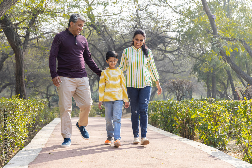 Obraz premium Happy family walking together holding hands at park