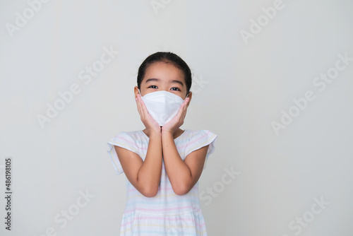 Asian kid showing happy expression while wearing medical mask during pandemic photo