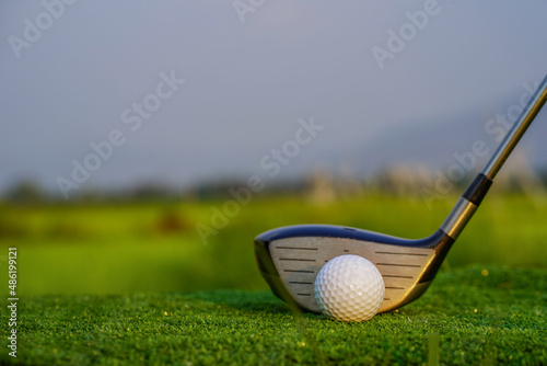 The golfer is pointing with a golf club. Showing a direction and measuring the trajectory. Green grass golf course