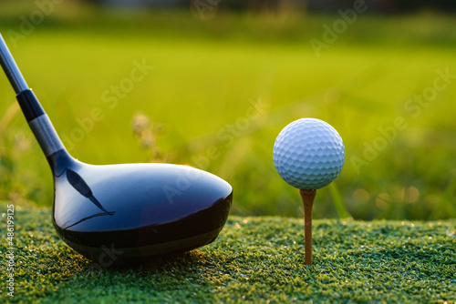 Golf club and ball on green grass ready to be struck on golf course background