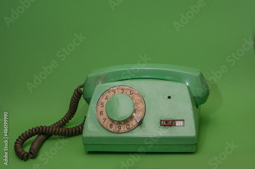 Old green retro vintage phone on green background. Minimalistic, monochromatic composition 
