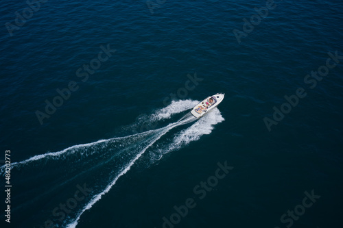 Big white boat with people in motion in the sea top view. Boat drone view. Speedboat moves fast on the water view from above. © Berg