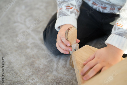 boy playing with a wooden plane on the floor