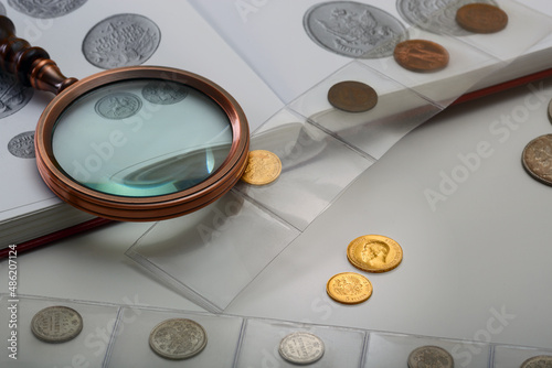 Numismatics. Old collectible coins and a magnifying glass on the table. photo