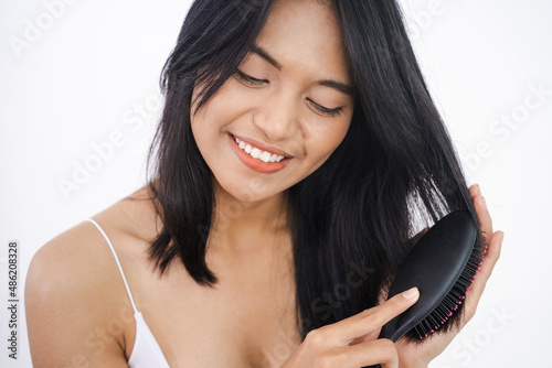 happy attractive asian woman brush her hair