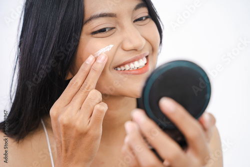 woman applying make up powder and blush on her cheeks