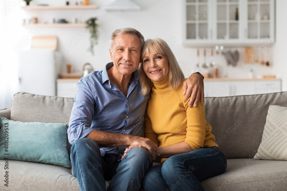 Loving Senior Couple Hugging Sitting On Sofa Posing At Home Loving Senior Couple Hugging Sitting On Sofa Posing At Home