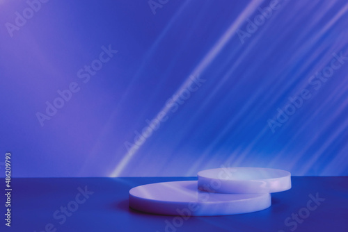 Abstract minimal scene - empty stage, circle podiums on dark blue background with neon disco light caustic effect. Pedestal for cosmetic, product, packaging mockups presentation