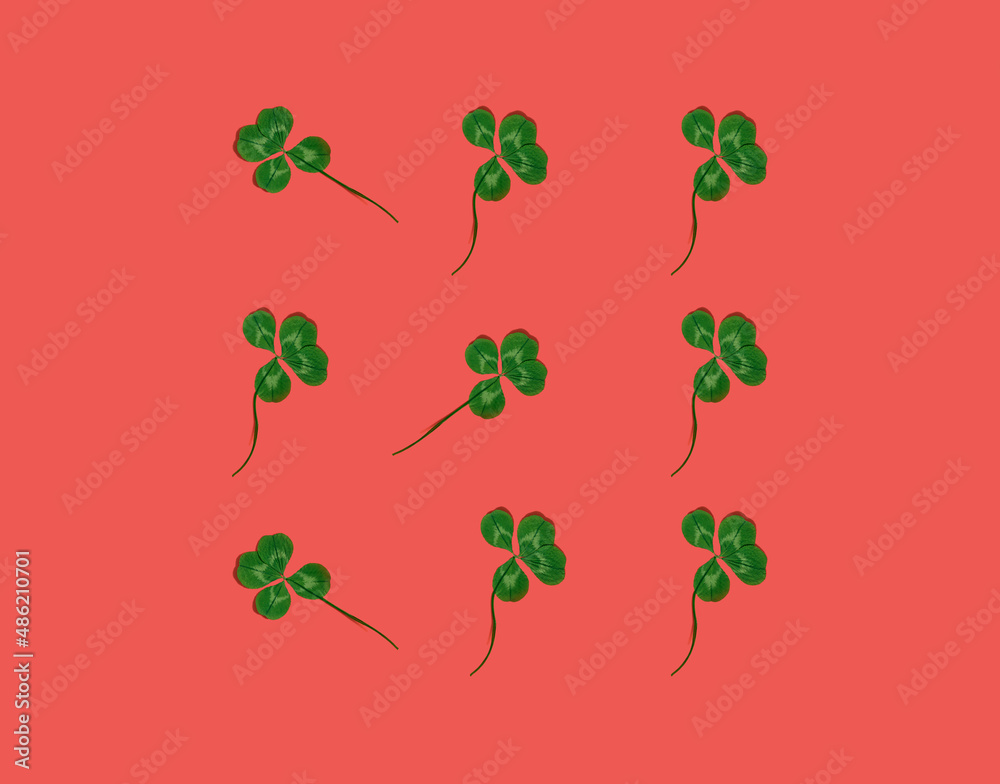 Four-leaf clovers against orange background, flat lay seamless pattern, minimal St. Patrick's Day concept for good luck