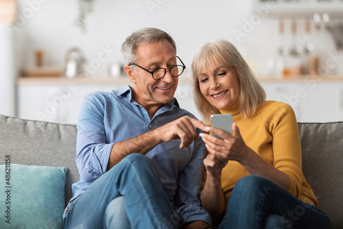 Quadro su tela Older Spouses Using Mobile Phone Sitting On Sofa At Home