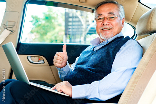 Adult senior executive luxury business old man sitting with laptop computer at back of car seat ,Technology transport lifestyles concept.