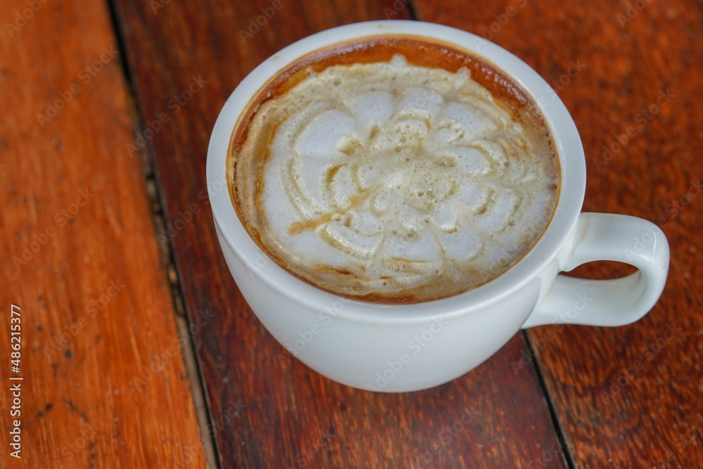 closeup hot caramel macchiato coffee in white ceramic cup on a wooden floor background, food, drink, copy space closeup hot caramel macchiato coffee in white ceramic cup on a wooden floor background, food, drink, copy space