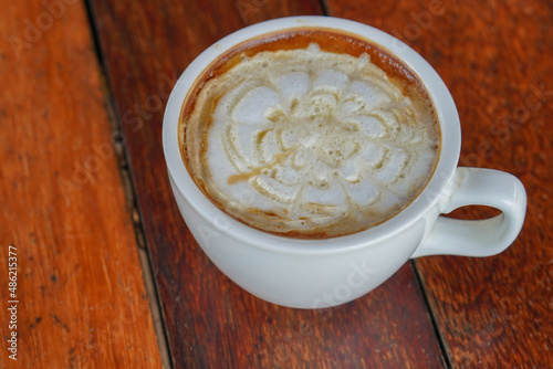 closeup hot caramel macchiato coffee in white ceramic cup on a wooden floor background  food  drink  copy space