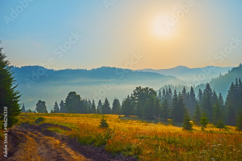 The golden foggy sunrise in mountains, Dzembronia village, Carpathians, Ukraine photo