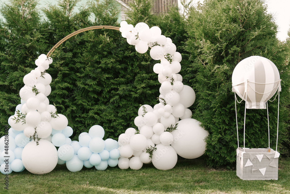Decorations for holiday party. A lot of balloons blue and white colors. Round photo zone with balls next to a ball with a basket for a child