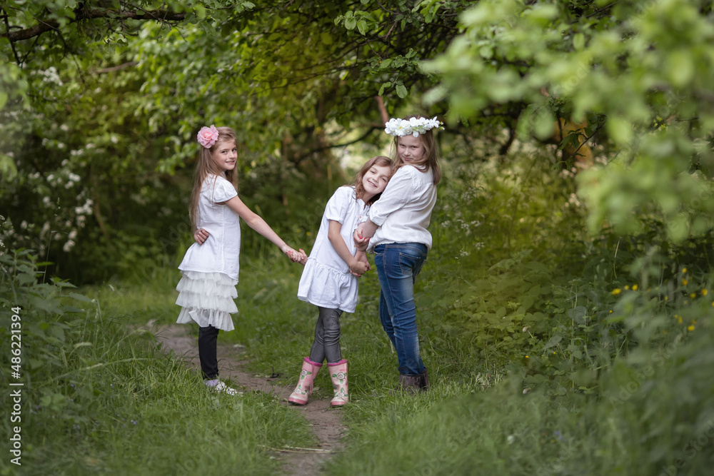 Three teenage girls in white blouses are laughing and playing, friendly hugging. Children's fun in nature in summer, holidays, happy childhood concept Three teenage girls in white blouses are laughing and playing, friendly hugging. Children's fun in nature in summer, holidays, happy childhood concept