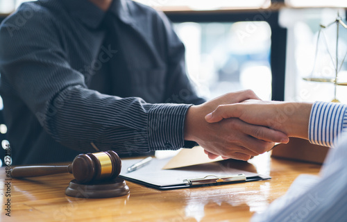 Businessmen shaking hands above the wooden desk in a modern office, close up. Unknown business people at meeting. Teamwork, partnership and handshake concept.