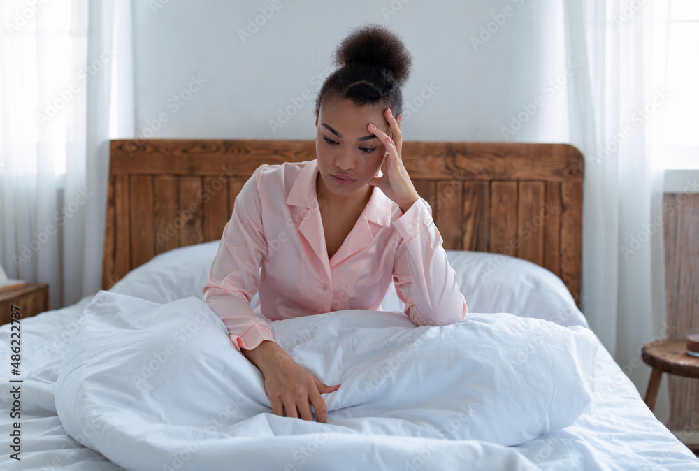 Depressed african american woman can't sleep, suffering from headache, stress and insomnia, sitting on bed, copy space - obrazy, fototapety, plakaty 