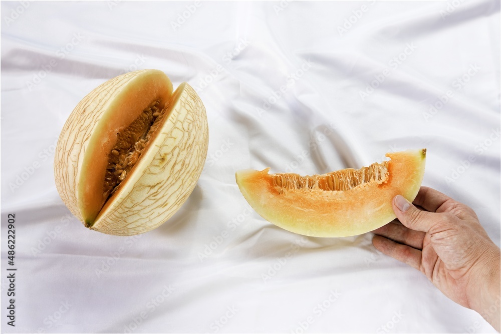 Waikiki Melon variety, cucumis melo hybrid fruit, white satin sheets background - obrazy, fototapety, plakaty 