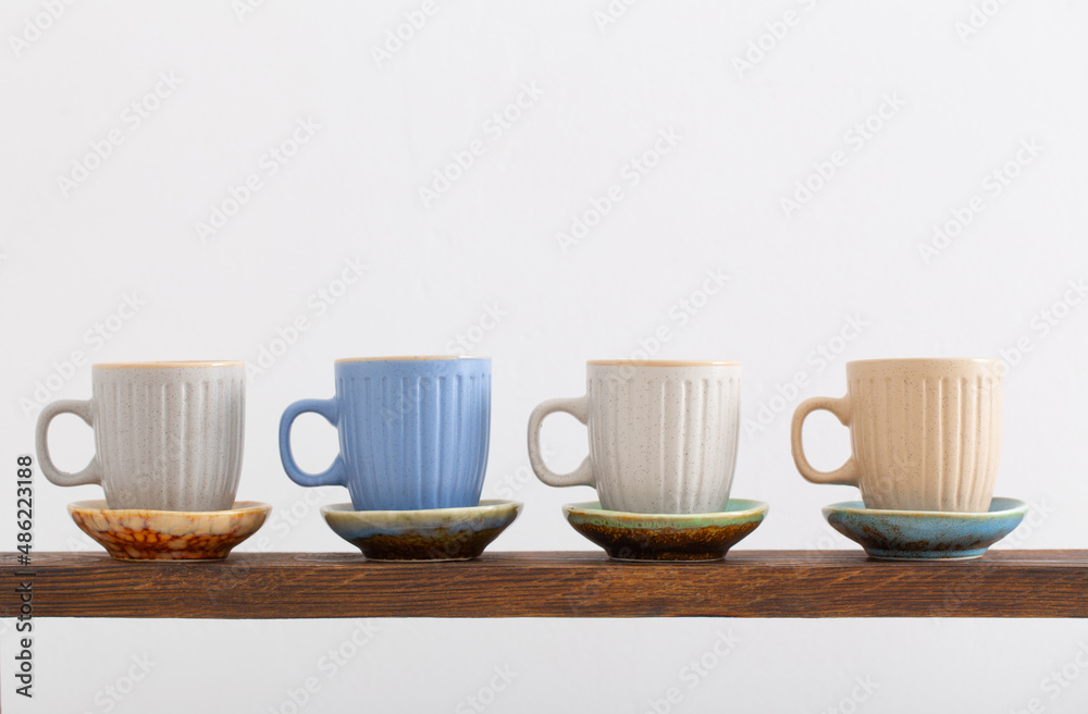 colorful cups on wooden shelf on white background colorful cups on wooden shelf on white background