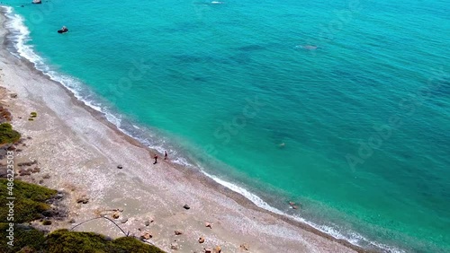 People walking on the beach near Aphrodite`s Rock in Cyprus. photo