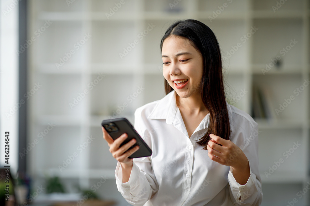 Portrait of a happy Asian businesswoman using mobile phone indoor, Asian businesswoman working in modern office.