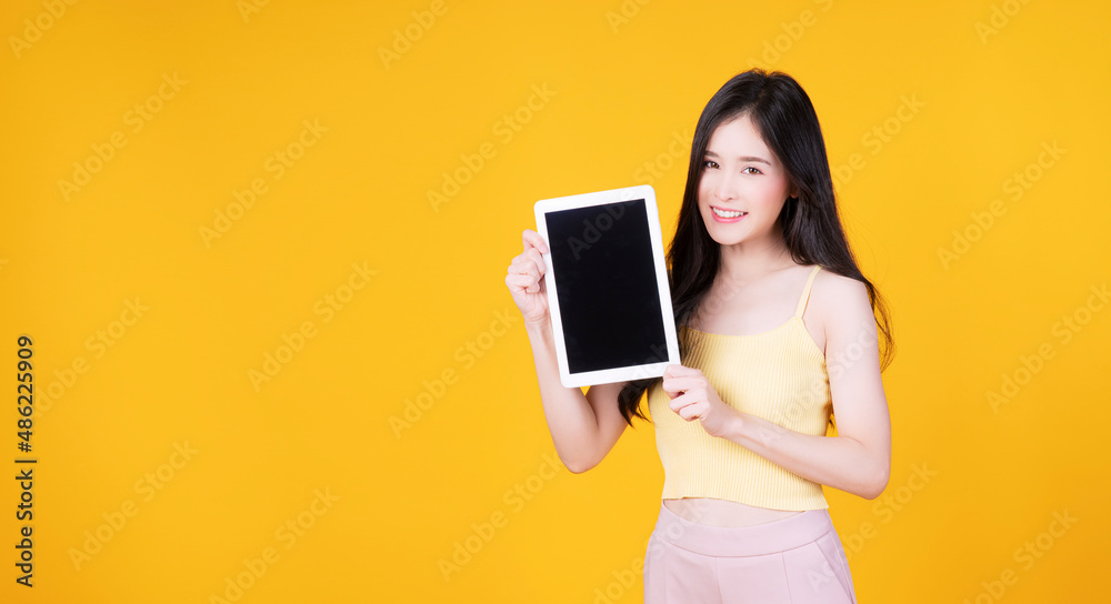 Asian employee woman showing screen tablet with blank monitor over isolated. Cheerful asia student girl holding digital tablet with smile on face on yellow background. Technology digital concept. Asian employee woman showing screen tablet with blank monitor over isolated. Cheerful asia student girl holding digital tablet with smile on face on yellow background. Technology digital concept.