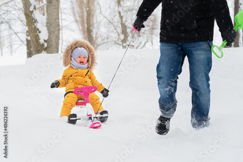Happy toddler 12-23 months happily enjoys riding a baby snowcat in a winter park