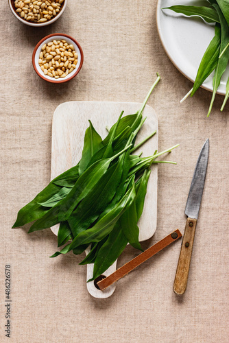 Freshly picked wild garlic,ramson on a white wooden on table with linen tableclouth. Spring herbs. Vegan helthy kitchen. Clean eating. Seasonal food.